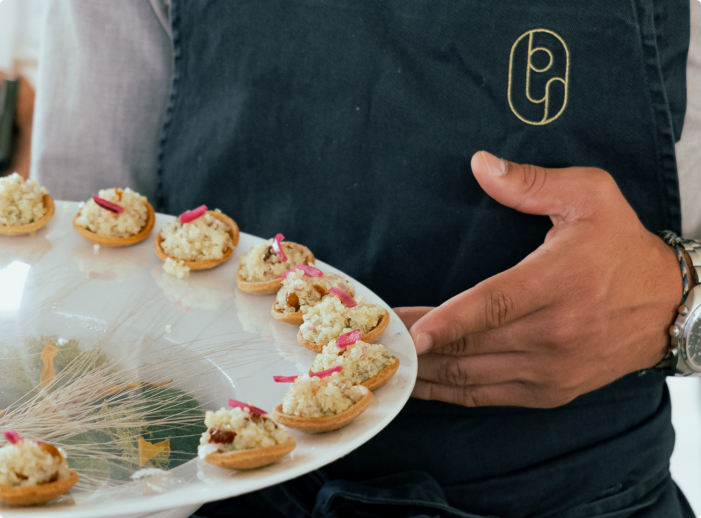 erveur portant un tablier avec le logo de la Maison Py-r, présentant un plateau d'amuses-bouches